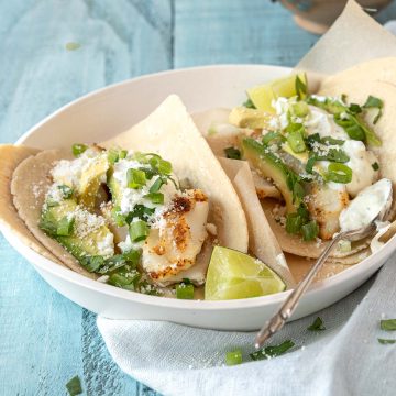 Fish tacos topped with with cilantro, green onions and yogurt sauce