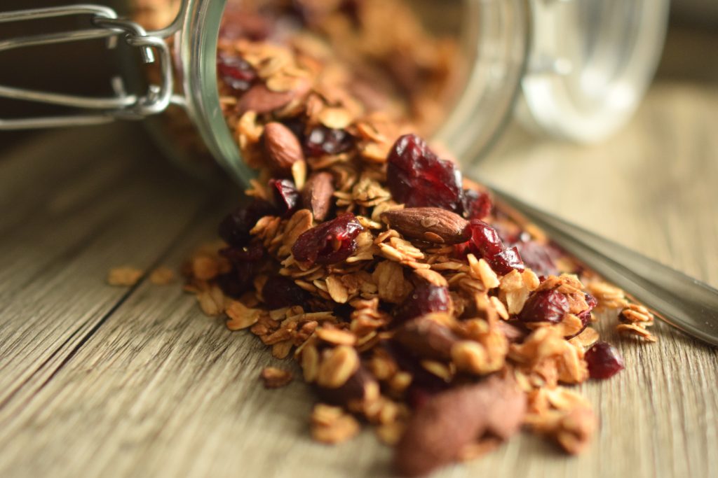 Granola with dried cranberries spilled out of a glass jar