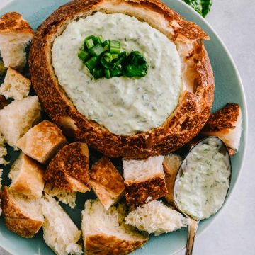 Spinach dip in a bread bowl with bread cubes