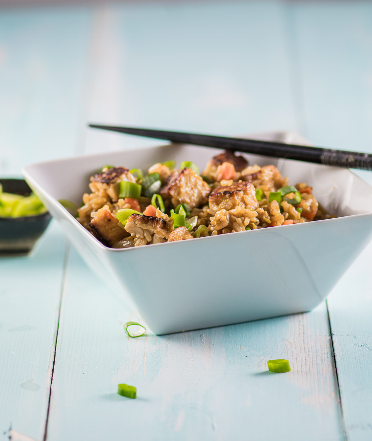 Tofu fried rice in a square white bowl with chopticks
