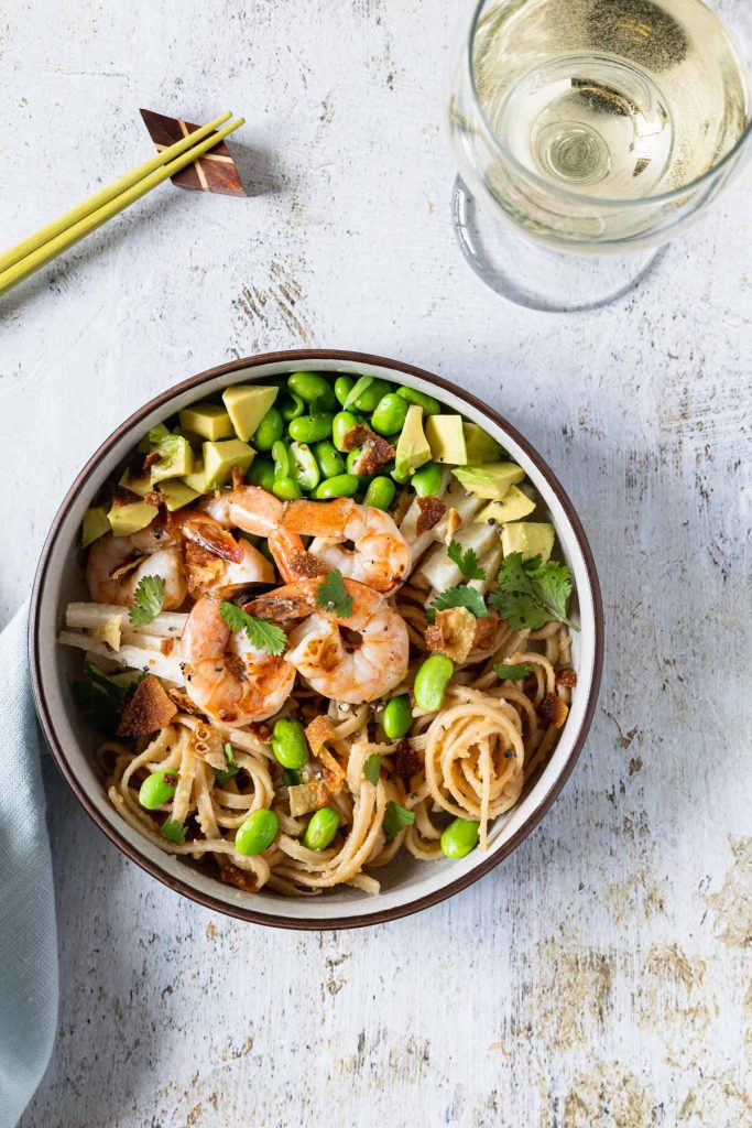 Overhead shot of grilled shrimp, edamame and avocado on top of udon noodles