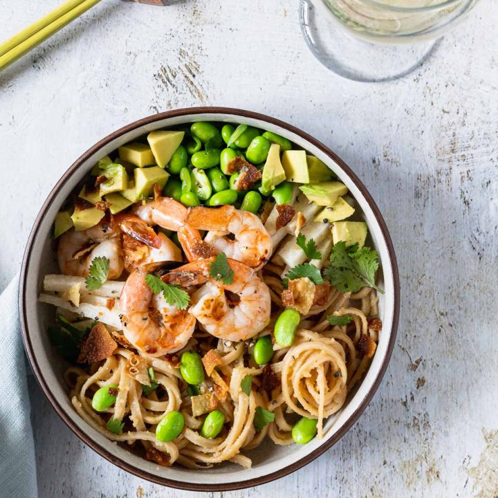 Overhead shot of grilled shrimp, edamame and avocado on top of udon noodles