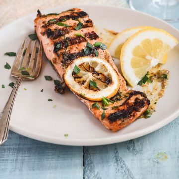 A grilled salmon filet topped with a slice of grilled lemon