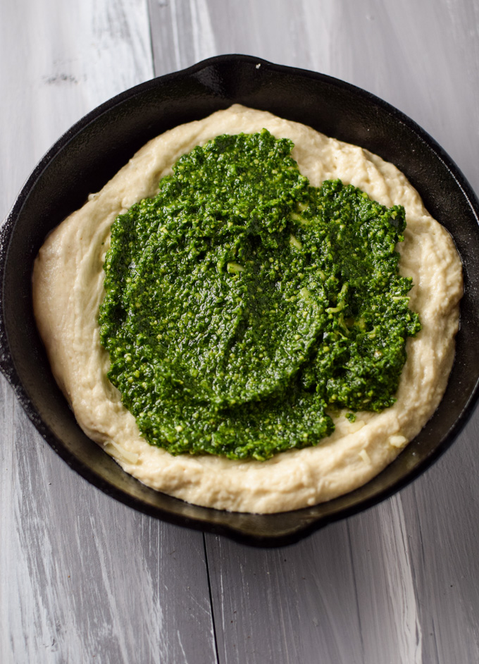 Pizza dough in mini skillet spread with kale pesto