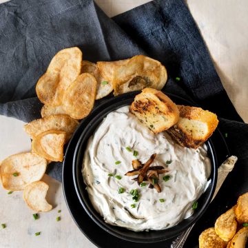 Overhead shot of a bowl of caramelized onion dip surrounded by potato chips