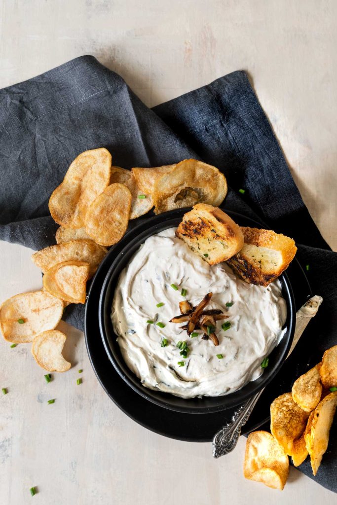 Overhead shot of a bowl of caramelized onion dip surrounded by potato chips