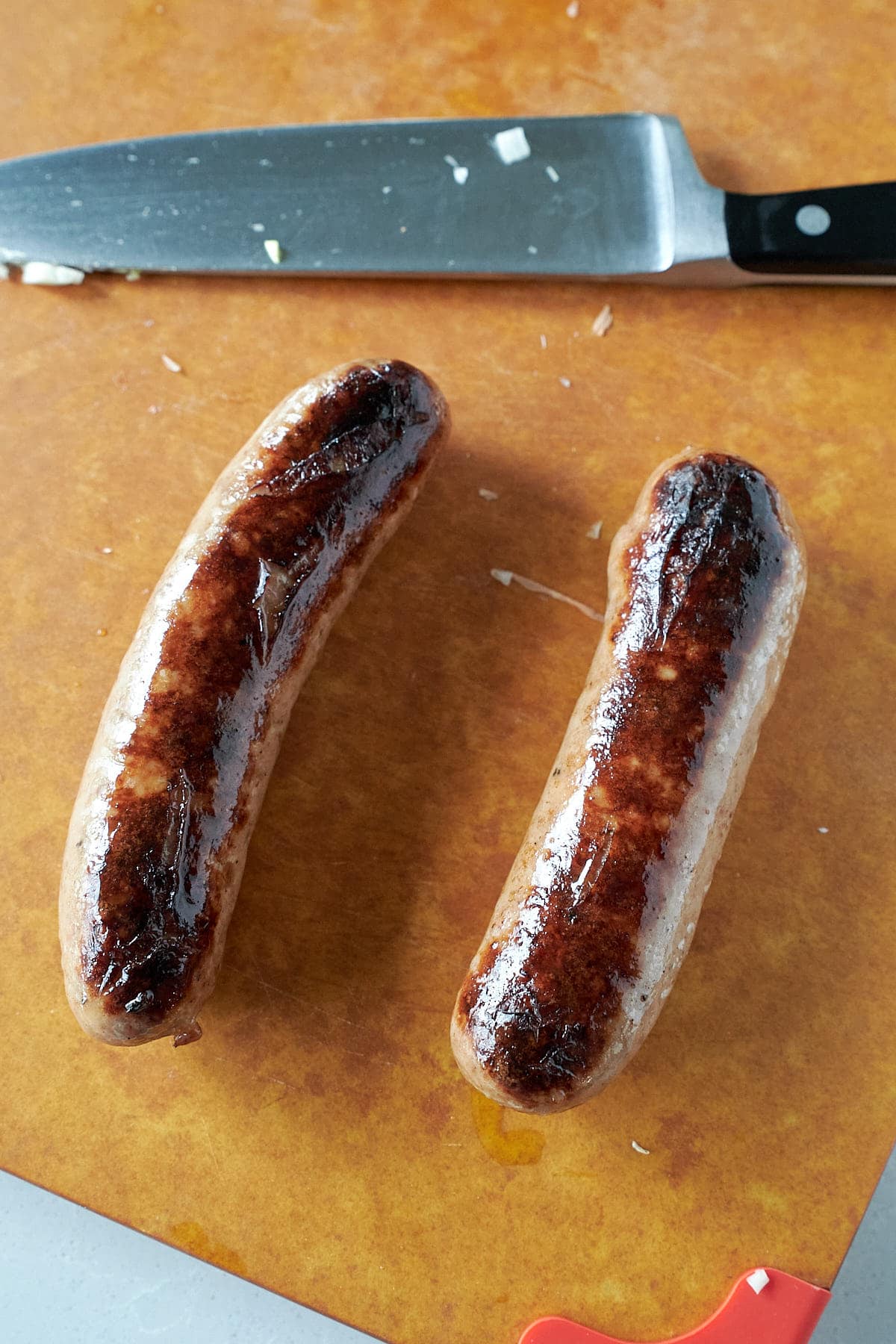 Two browned sausage links on a cutting board