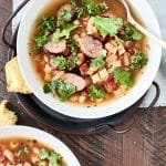 Two bowls of tomato based soup with sauage, pasta, white beans and kale