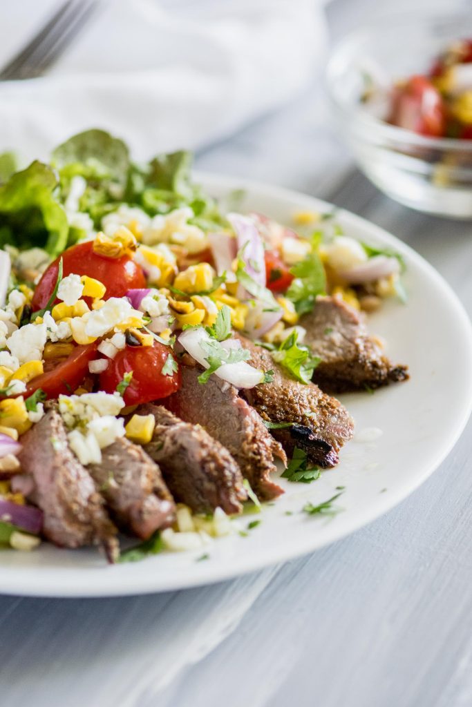 Salad with grilled steak, tomatoes, blue cheese and avocado on a white plate