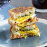 Egg, cheese and pesto sandwich halves stacked on a blue plate