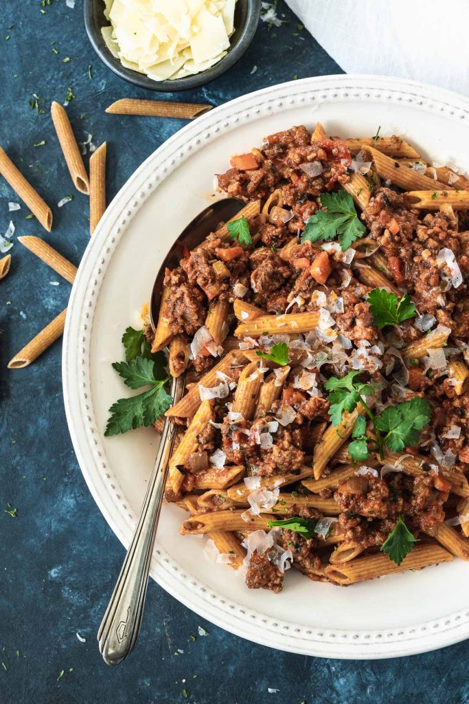 Close up overhead shot of penne pasta with bolognese sauce