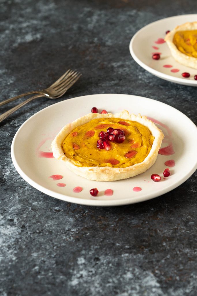 Butternut squash tart topped with pomegranate seeds and simple syrup