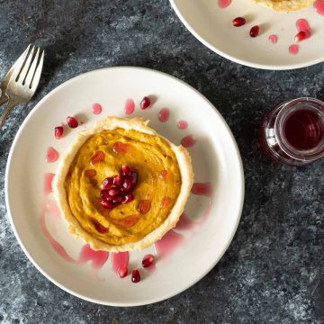 Overhead shot of two butternut squash tarts on cream plates