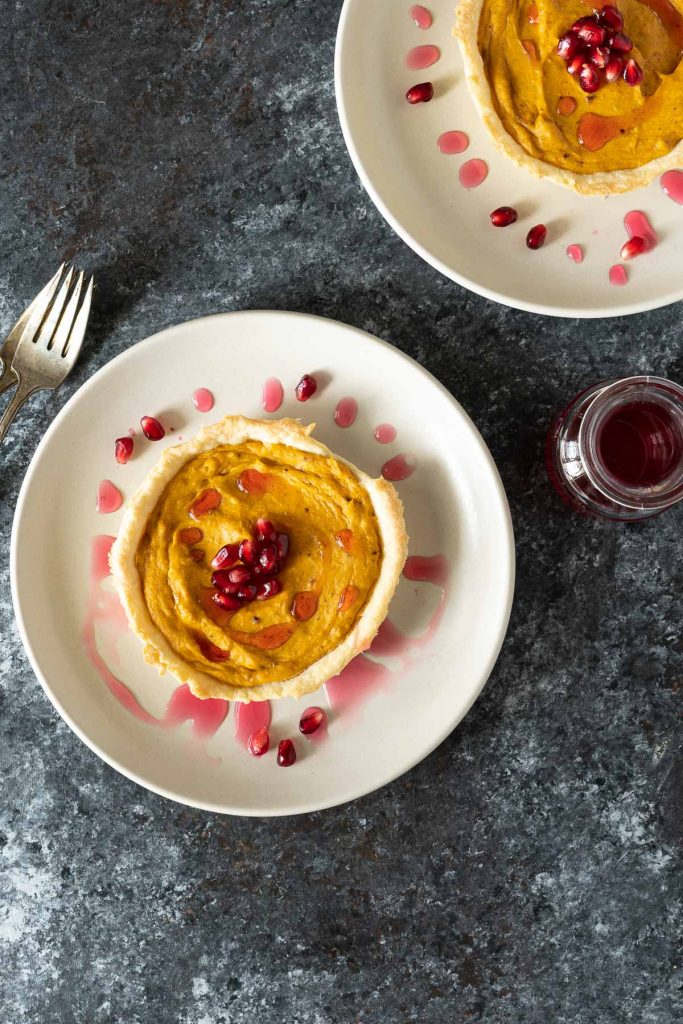 Overhead shot of two butternut squash tarts on cream plates