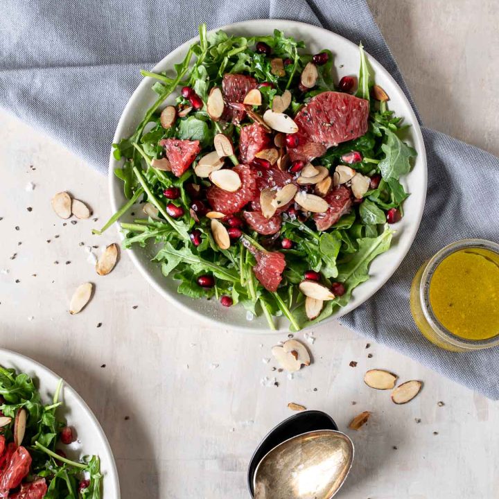 Arugula salad topped with toasted almonds, grapefruit and pomegranate