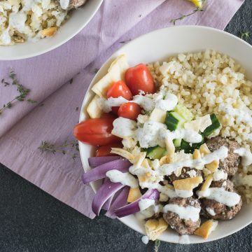 Bowl of cauliflower rice, lamb meatballs, red onions, cucumber and tomatoes