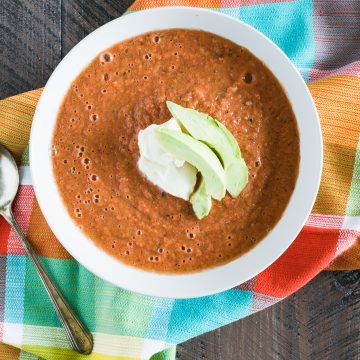 Traditional tomato gazpacho topped with avocado slices and creme fraiche