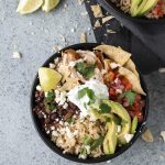 Overhead shot of a chicken burrito bowl topped with avocado slices and pico de gallo