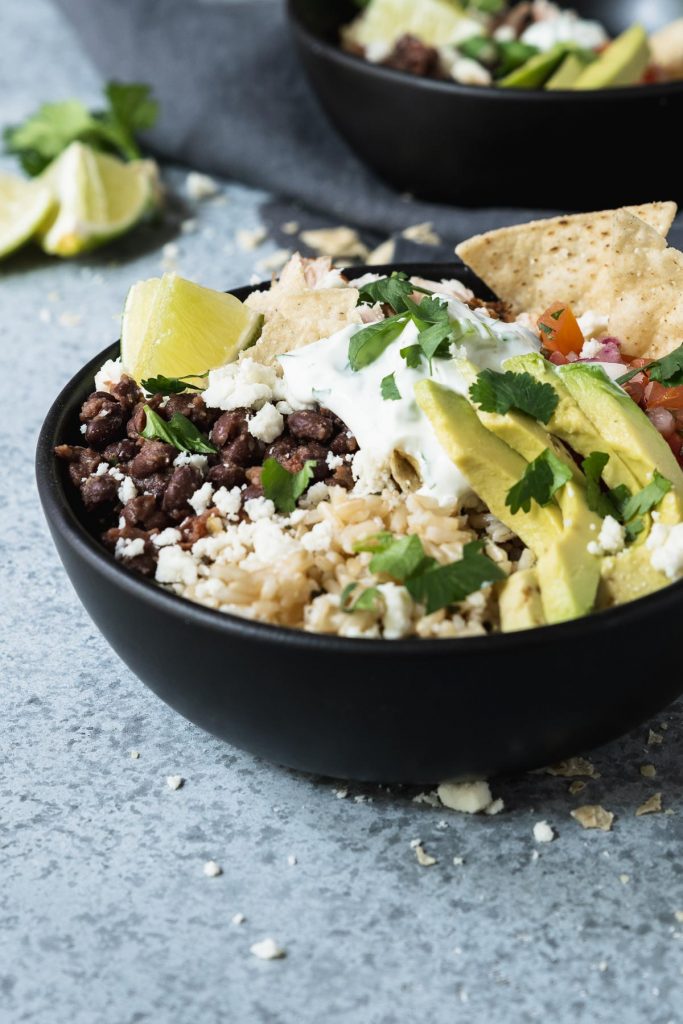 Brown rice bowl topped with shredded chicken, avocado, black beans and pico de gallo