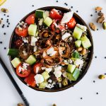 Dark bowl filled with beluga lentil and basmati rice salad topped with crispy shallots and pistachios, chopstick on the side