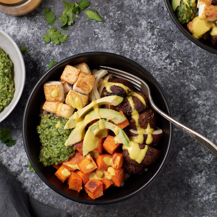 Roasted sweet potatoes, mushrooms and tofu topped with avocado all in a grey bowl