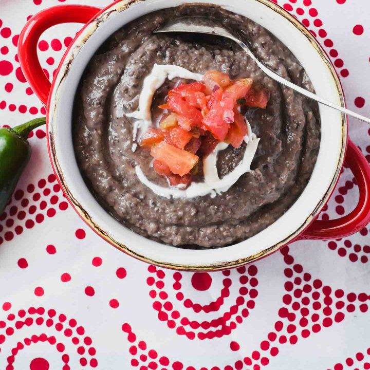 Creamy black bean soup with pico de gallo topping on a red and white napkin