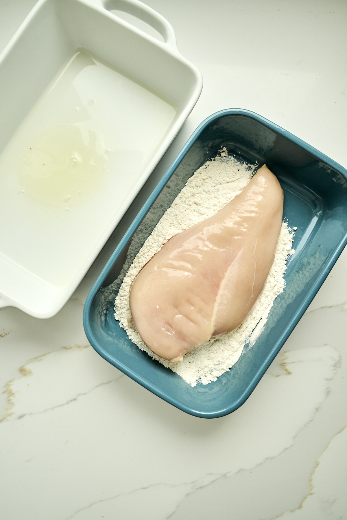 Chicken breast being dipped in flour