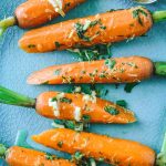 Bright orange steamed carrots with lime gremolata on a teal plate