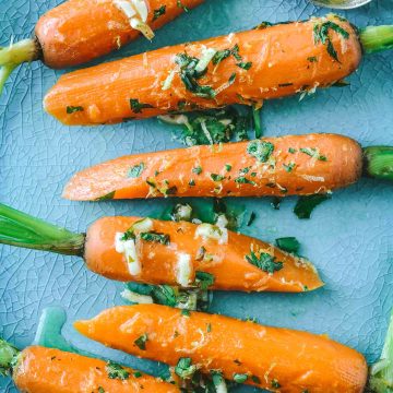 Bright orange steamed carrots with lime gremolata on a teal plate