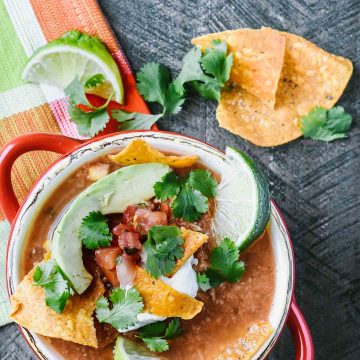 Slow cooker chicken tortilla soup topped with avocado, pico de gallo and lime wedges