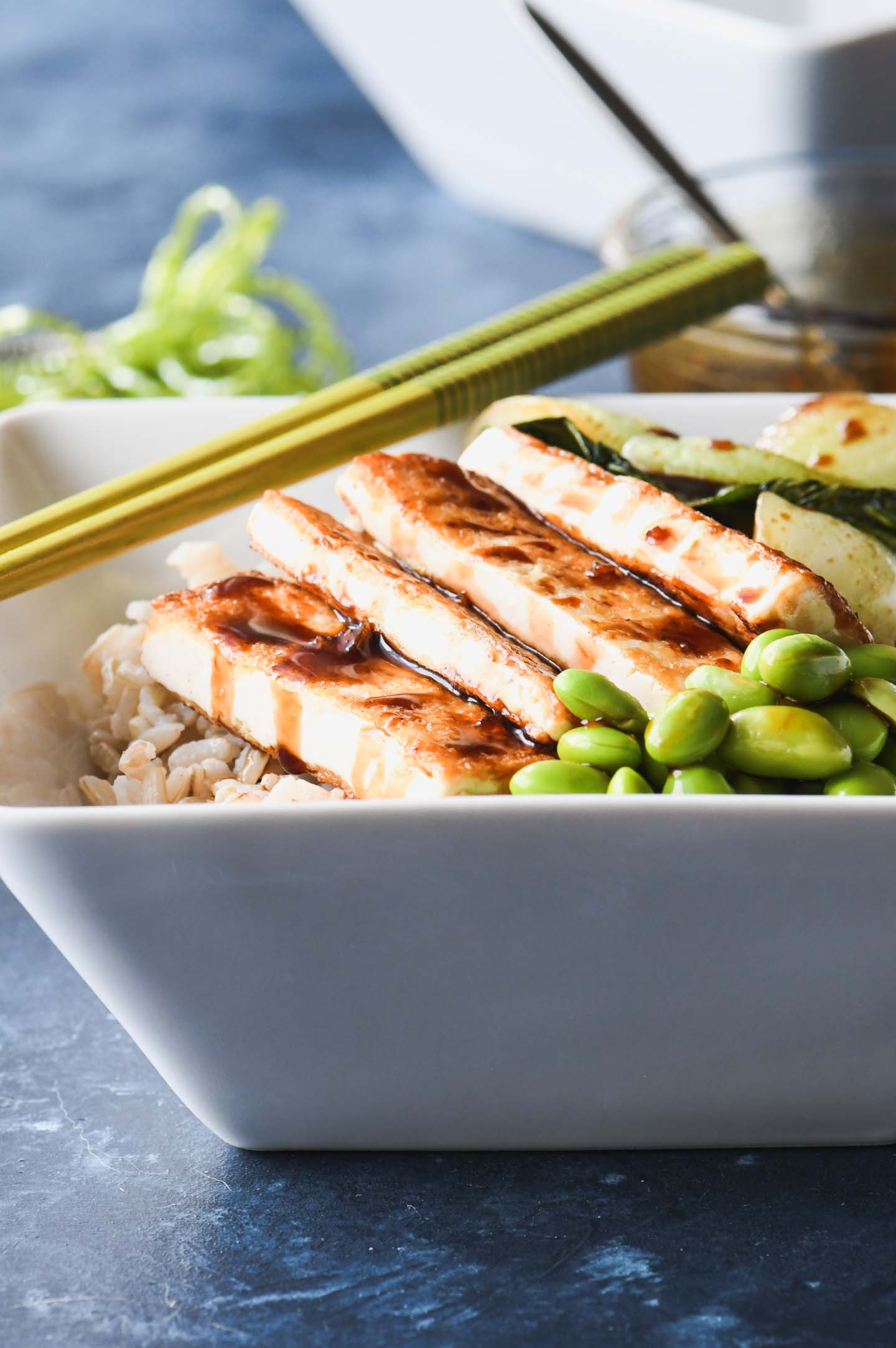 Crispy tofu rice bowl topped with bok choy, edamame and teriyaki glaze