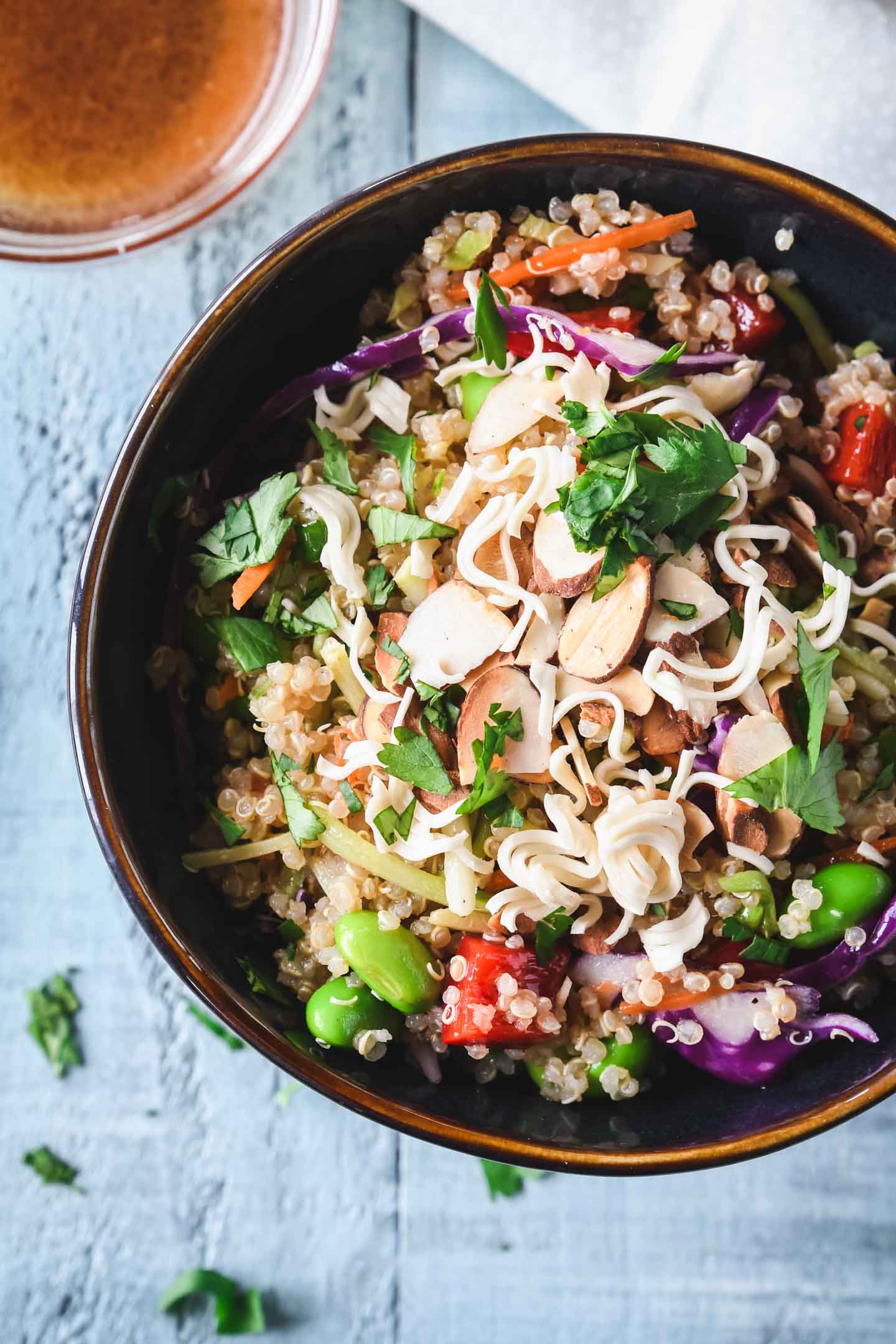 Asian quinoa salad in a dark bowl with dressing on the side