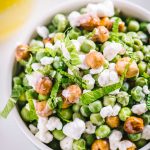 English pea salad topped with candied hazelnuts and goat cheese with a side of meyer lemon vinaigrette