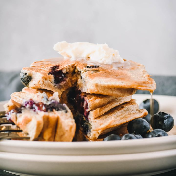 Stack of blueberry protein pancakes with a bit cut out.