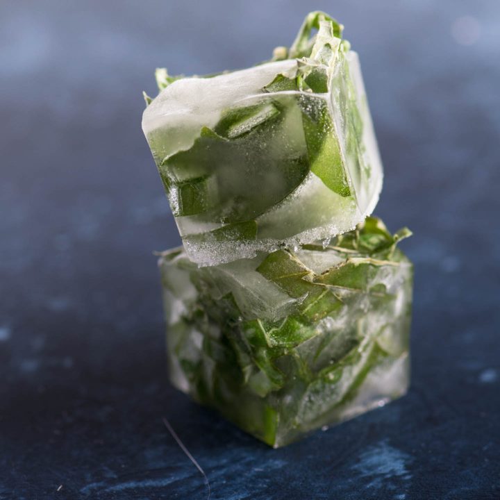 Stacked herb ice cubes on a blue background