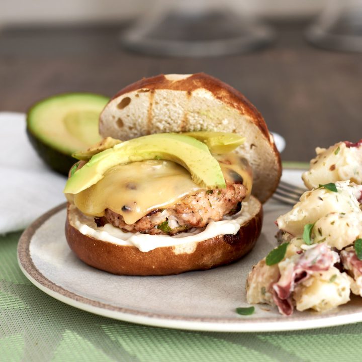 Grilled turkey burger topped with swiss cheese and avocado, served with a side of potato salad