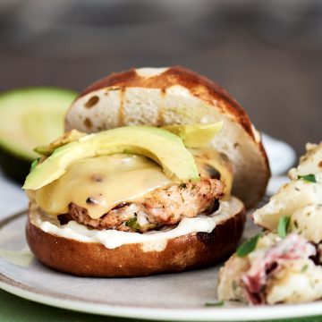 Turkey burger patty on a toasted bun topped with swiss cheese and avocado
