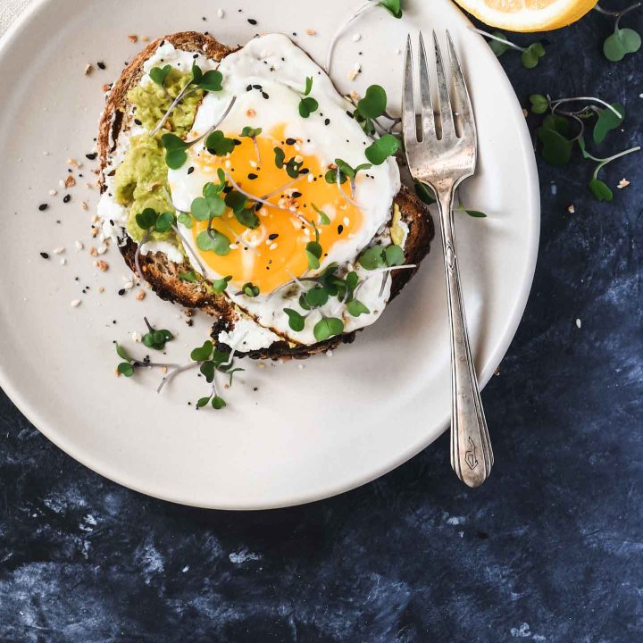 Whole grain toast topped with ricotta, avocado and a runny egg