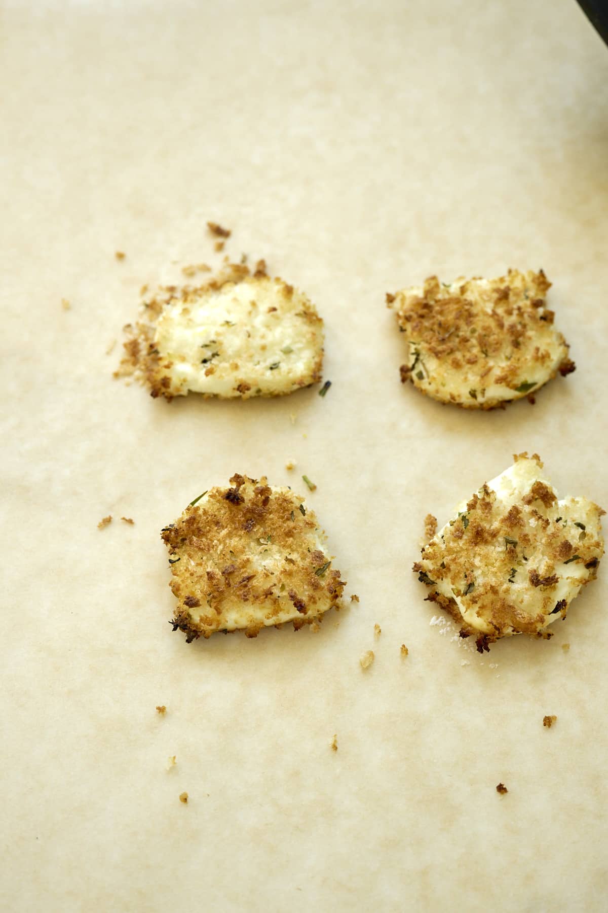 Baked goat cheese rounds on a piece of parchment paper