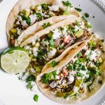 Three pork tacos topped with grilled corn salsa and cilantro lime sauce