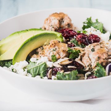 Close-up of kale salad greens topped with turkey meatballs and avocado