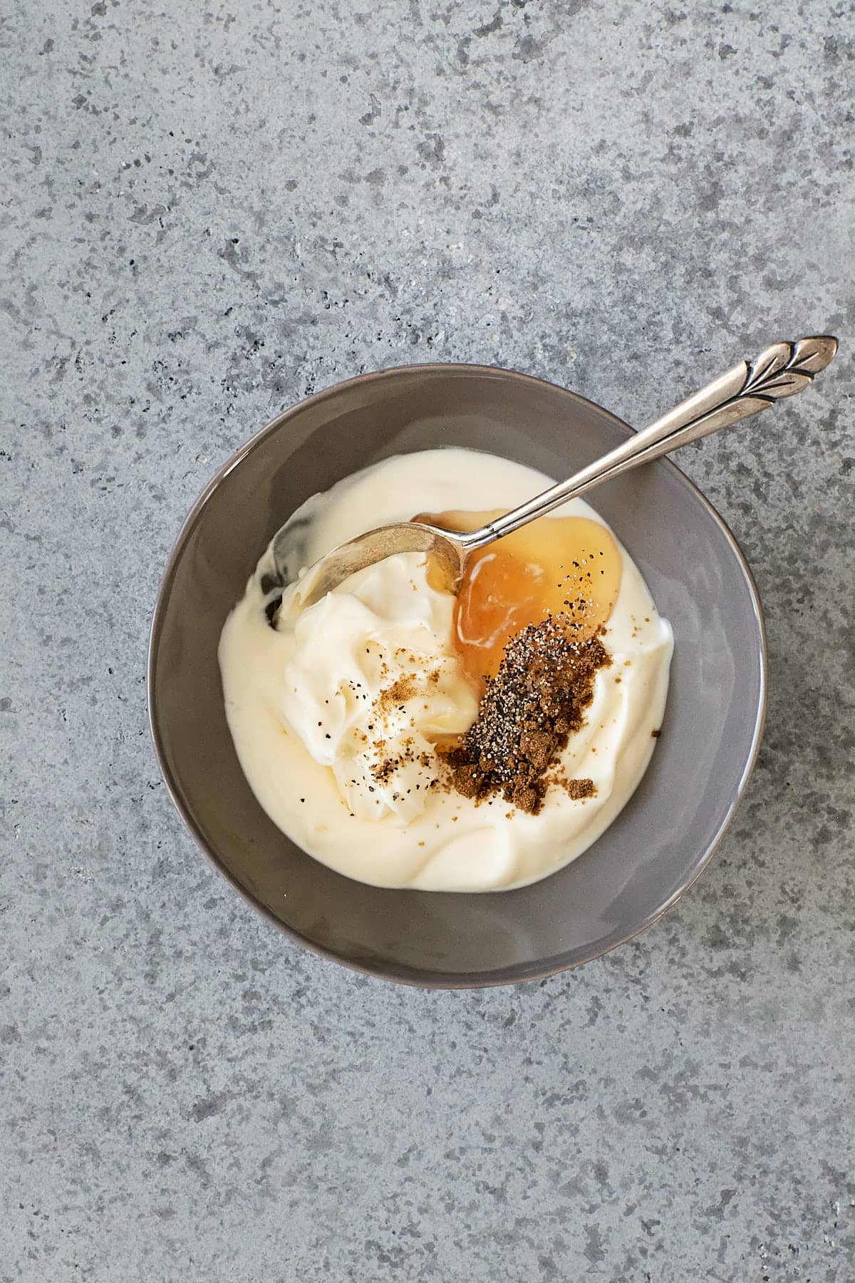 Creme fraiche and mascarpone with honey, cumin and pepper in a small grey bowl