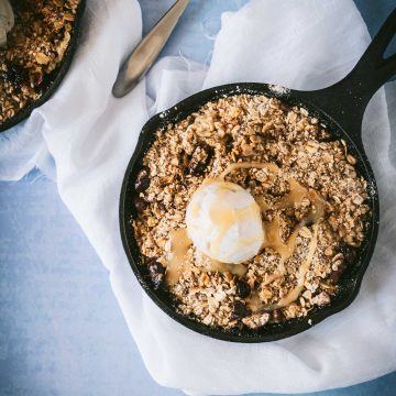 Apple crisp in a mini cast iron skillet with ice cream on tope
