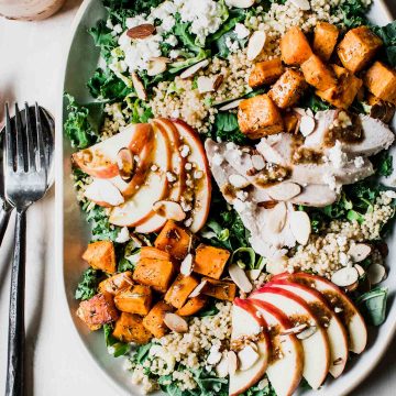 Chopped kale salad topped with sweet potatoes, apples, quinoa and goat cheese