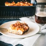 Slice of breakfast casserole on a plate with entire casserole in background.