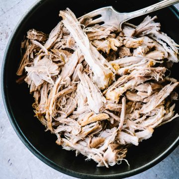 Cooked pulled pork in a black bowl
