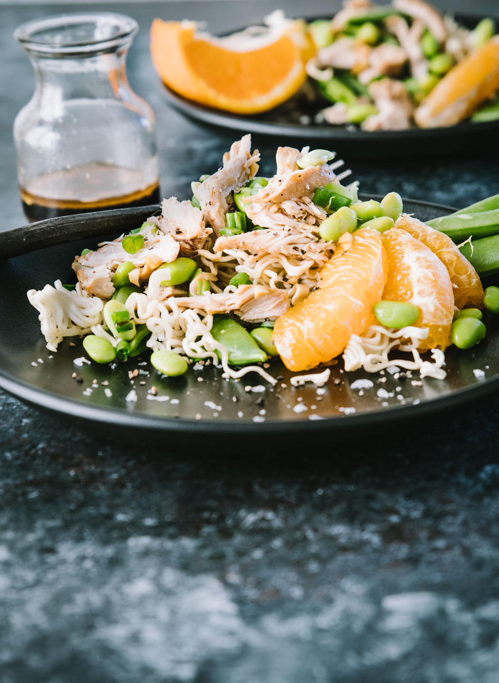 Asian Chicken salad with a ramen cake on a dark plate and dark background