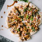 Homemade pizza topped with Thai chicken, carrots, cilantro and red onion