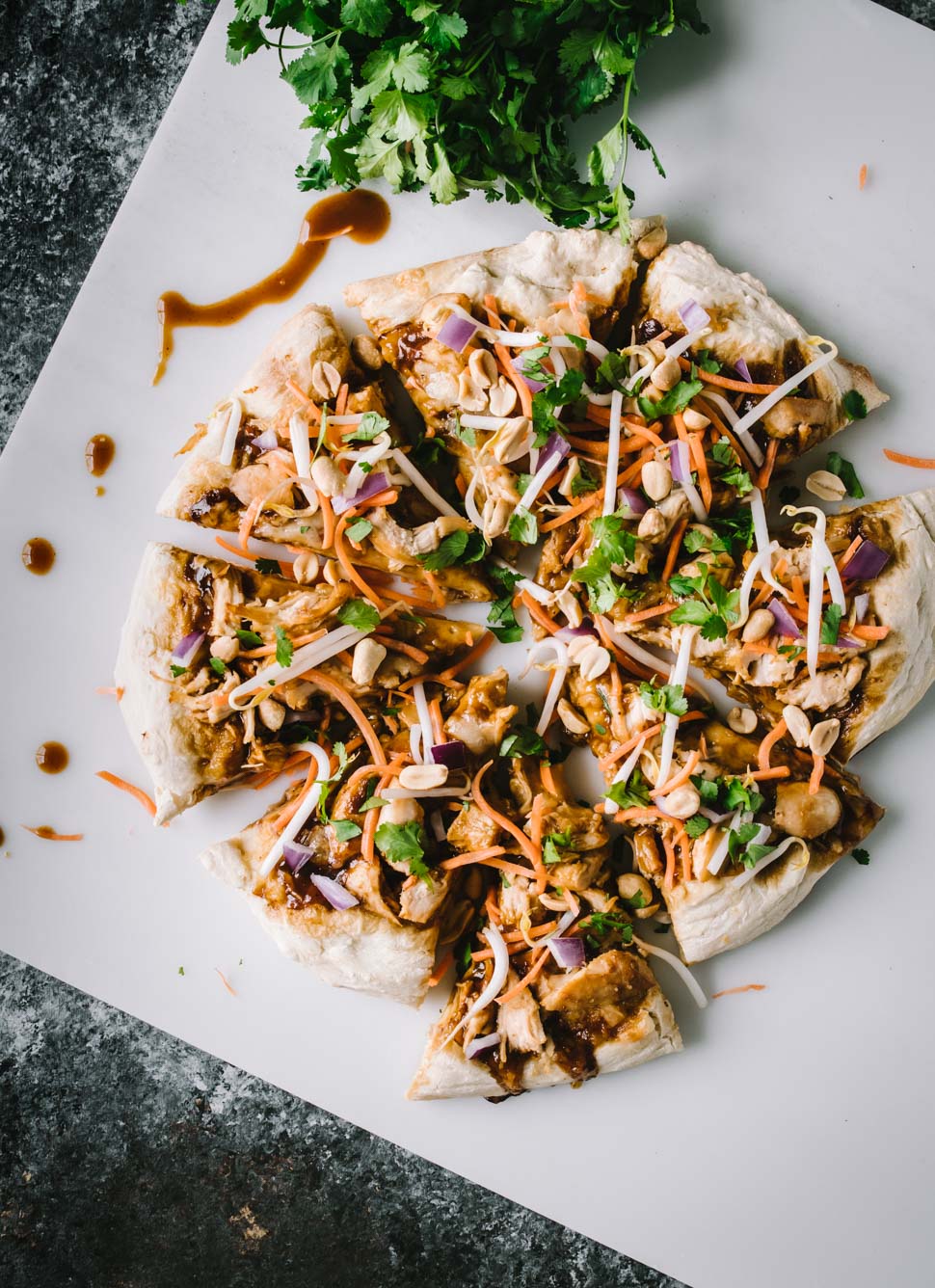 Homemade pizza topped with Thai chicken, carrots, cilantro and red onion