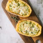 Two spaghetti squash halves on a brown cutting board shot from overhead